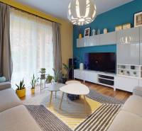 Nappali a családi házban színes falakkal, fa dekoros padlóval és szobanövényekkel.