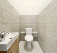 Iroda szürke csempékkel és mosdóval ellátott mosdója.