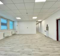 Irodák fa hatású padlóval, fehér falakkal és nagy ablakokkal.