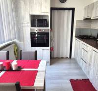 Konyha étkezőasztallal, fehér redőnyökkel és konyhabútorral egy kétszobás lakásban.