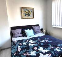 Hálószoba egy kétszobás lakásban ággyal, képpel és tükrös szekrénnyel.