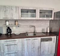 Konyha egy kétszobás lakásban, piros hűtőszekrénnyel és fa dekorációjú padlóval.