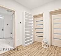 Családi ház belső tere fa dekorációjú padlóval, ajtókkal és fehér polccal.