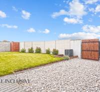 Kert a családi ház mellett Gabčíkovo-ban, gyep, kavicsok és fa kerítés.