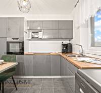 Konyha szürke konyhabútorral, beépített sütővel és mikrohullámú sütővel egy családi házban.