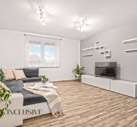 Nappali egy családi házban kanapéval, televízióval és fa dekorációjú padlóval.