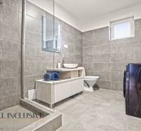 Fürdőszoba családi házban csempékkel, zuhanyzóval, mosógéppel és mosdóval.