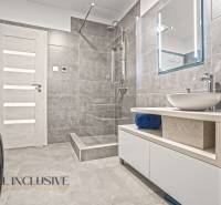 Fürdőszoba zuhanyzóval, fa deszkán lévő mosdóval és mosógéppel a családi házban.