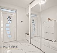 Családi ház belső tere fehér szekrényekkel, tükörrel és márvány mintás padlóval.