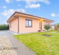 Családi ház Bősön, amelyet zöld növényzet, térkő és egy kis fa vesz körül a kertben.