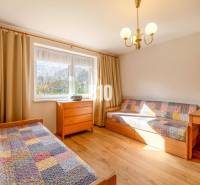 Szoba családi házban ágyakkal, fa dekorációval és színes takarókkal.