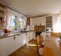 Konyha egy családi házban, fa dekoros padlóval és világos bútorokkal.