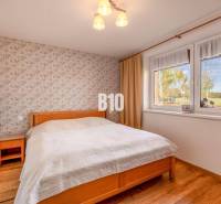 Hálószoba családi házban virágos tapétával és fa dekoros padlóval.