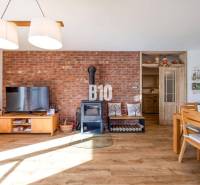 Családi ház belső tere téglafallal, kályhával és fa dekorációjú padlóval.