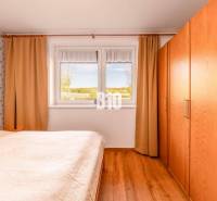 Hálószoba családi házban, fa dekoros padlóval és kilátással az ablakból.