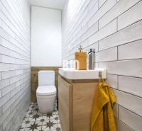 Keskeny fürdőszoba csempékkel, WC-vel és mosdóval egy háromszobás lakásban.