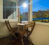 Egy 3 szobás lakás erkélye Nyitrán, fából készült bútorokkal és kilátással a zöldre.