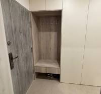 Előszoba szekrényekkel és fogasokkal egy kétszobás lakásban, fa dekoráció az ajtókon.