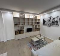 Nappali egy kétszobás lakásban kanapéval, polccal és fa dekorációjú padlóval.