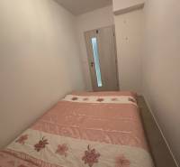 Hálószoba egy kétszobás lakásban, virágmintás ággyal és világos falakkal.