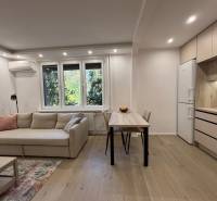 Nappali kanapéval, étkezőasztallal és konyhával egy kétszobás lakásban.