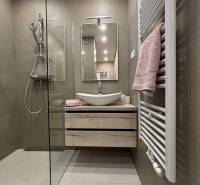 Fürdőszoba egy kétszobás lakásban mosdóval, zuhanyzóval és törölközővel a radiátoron.