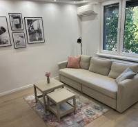 Nappali egy kétszobás lakásban, kanapéval, asztalokkal és fényképekkel a falon.