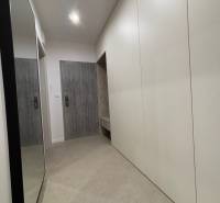 2 szobás lakás előszobája fehér szekrényekkel és tükörrel a falon.