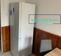 Konyha egy kétszobás lakásban, hűtőszekrény, fa burkolat, szürke szék, étkezőasztal.