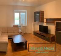 Nappali bézs kanapéval, fa bútorokkal és fa dekorációjú padlóval.