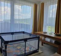 Gyerekkarám és asztal a kétszobás lakás nappalijában kilátással.