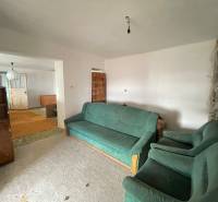 Nappali egy családi házban szőnyegekkel és zöld kárpitozott bútorokkal.