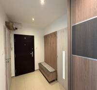 A háromszobás lakás előszobája szekrénnyel és fogassal, világos környezetben.