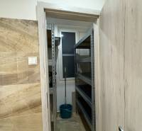 Kis raktár egy háromszobás lakásban polcokkal és vödörrel.