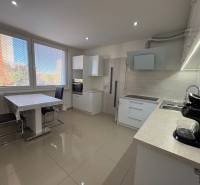 A háromszobás lakás konyhája nagy ablakokkal, étkezőasztallal és világos padlóval.