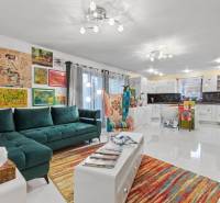 Színes nappali családi házban kanapéval, karosszékkel és művészettel a falakon.