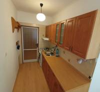 Konyha fa mintázatú padlóval, konyhabútorral és gáztűzhellyel egy kétszobás lakásban.