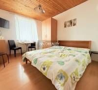 Szállodai szoba kétágyas ággyal, televízióval, asztallal és fa dekorációjú padlóval.