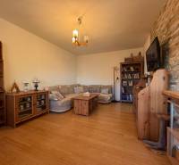 Nappali kanapéval, fa dekoros padlóval, könyvtárral és falra szerelt televízióval.