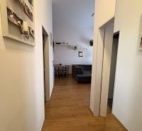 Folyosó egy kétszobás lakásban, fa dekoros padlóval és falakon lévő dekorációkkal.