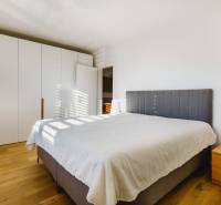 Hálószoba nagy ággyal, ruhásszekrénnyel és fa mintázatú padlóval egy családi házban.