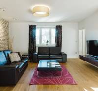 Nappali bőrkanapéval, téglafallal és fa mintázatú padlóval egy családi házban.