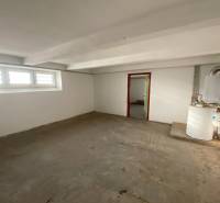 Üres szoba egy családi házban ablakokkal és kazánnal.