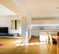 Családi ház nyitott konyhával, fa dekorációjú padlóval és étkezőasztallal.