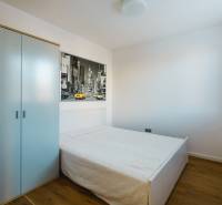 Hálószoba családi házban, egyszerű ággyal, szekrénnyel és fa dekorációjú padlóval.