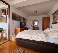 Öt vagy több szobás lakás szobája ággyal, művészettel a falakon és fa dekorációjú padlóval.