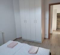 Hálószoba egy faházban fehér ruhásszekrénnyel és fa mintázatú padlóval.