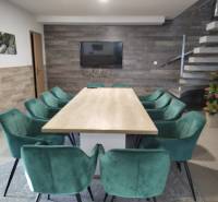 Ebédlő faházban fa dekorációval, lépcsővel és zöld székekkel az asztal körül.