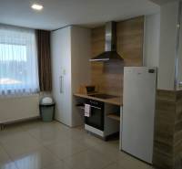 A kunyhó belső tere konyhasarokkal és fehér háztartási gépekkel, csempézett padlóval.