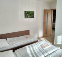 Két ágy a szobában, egy képpel a falon és ajtóval a házikóban.